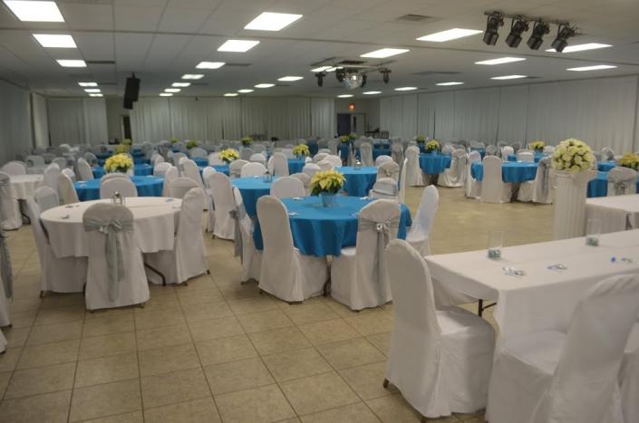 This blue and white themed reception features blue and white table linens and white chair covers accented with silver chair sashes.