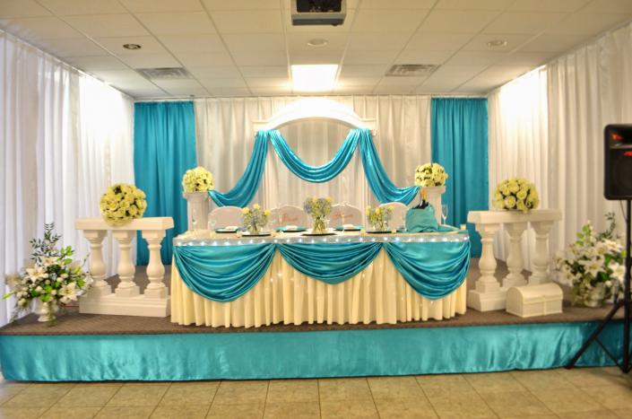 Beautiful, elegant and sophisticated wedding decor. Teal and white drapery enhance the table for the bride and groom.