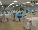 This blue and white themed reception features blue and white table linens and white chair covers accented with silver chair sashes.