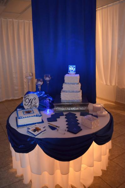 Round lit up cake table with blue and white drapery. 