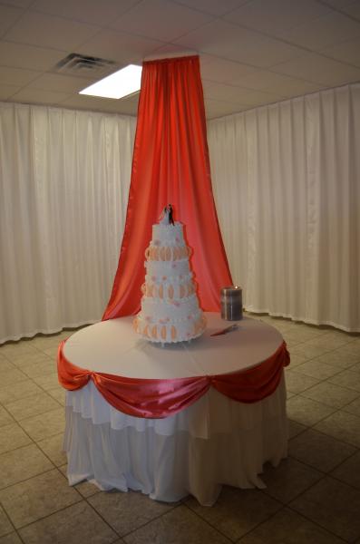 Wedding cake table with red and white drapery.