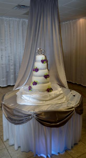 Wedding cake on to of a decorated table with blue light. 